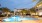 a swimming pool in front of a building with palm trees